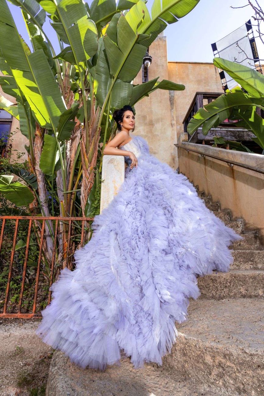 A lavender ostrich feather gown with a full train on a garden staircase