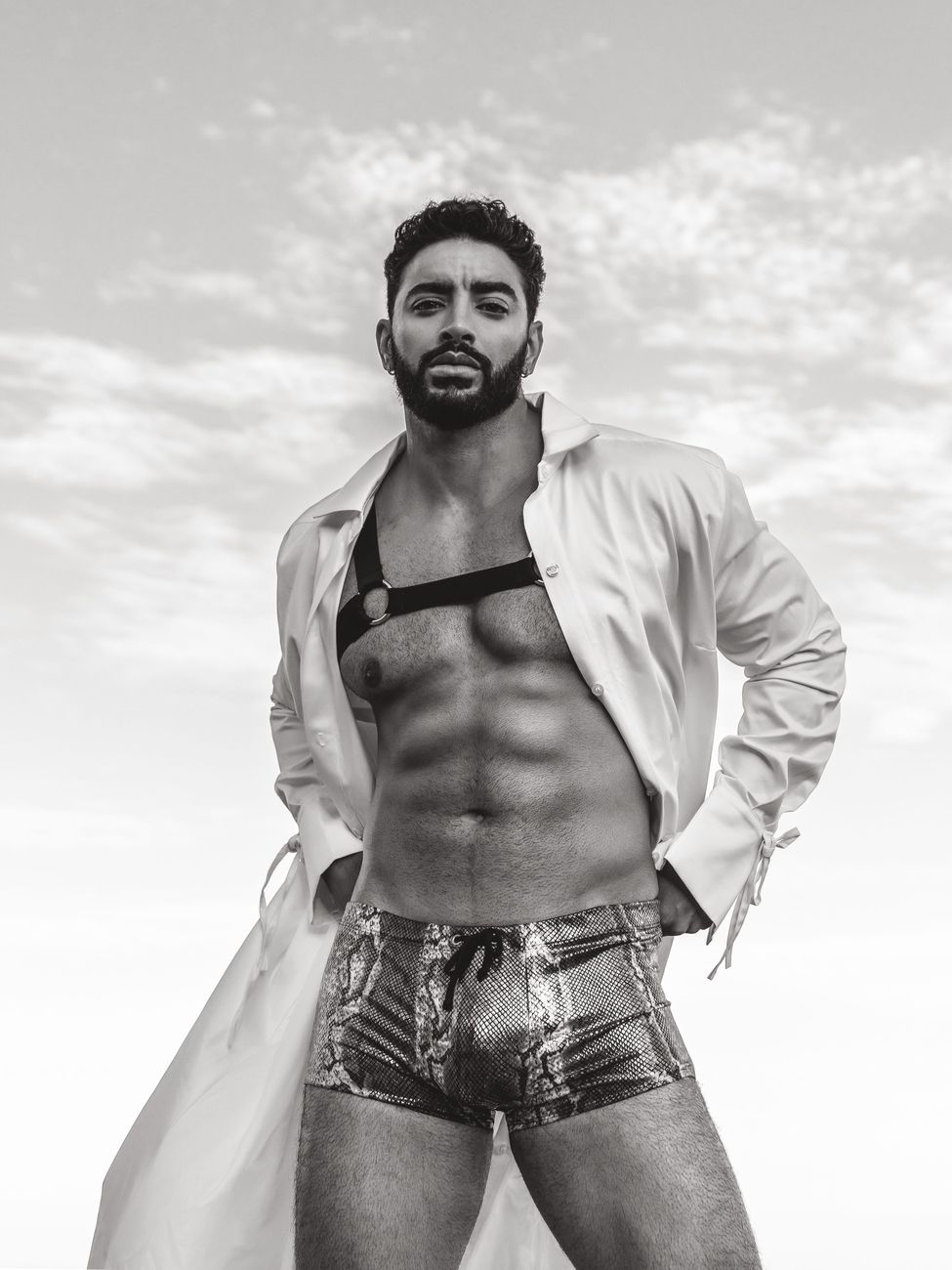 Menswear editorial: an open white shirt and denim shorts against open sky