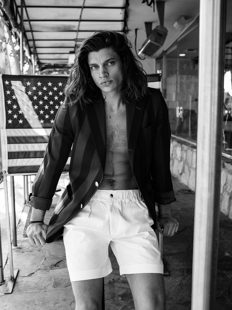 Menswear editorial: a leather jacket and white shorts beneath an American flag