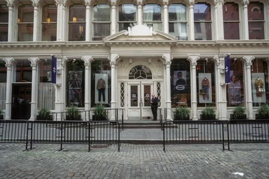 The pop-up's cast-iron storefront on a cobblestone street, with campaign imagery in every window